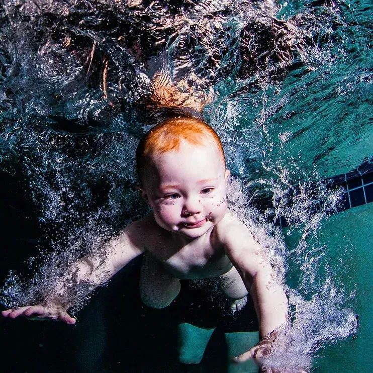 A baby underwater in a swimming pool.