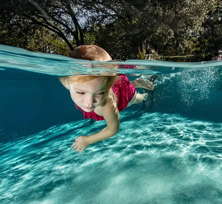 A child swimming underwater holding their breath.
