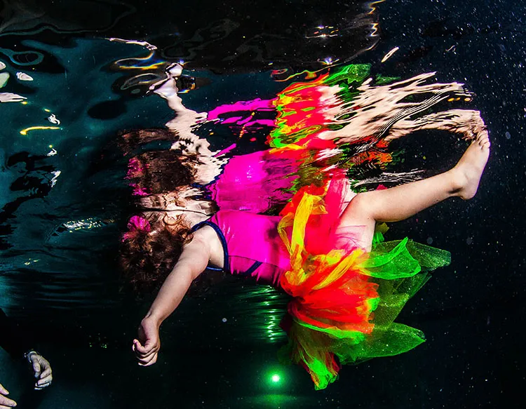 An infant girl floating on her back in a pool.