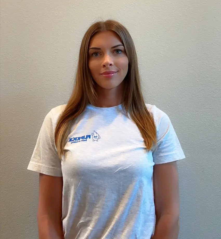 Headshot of swim instructor Kim Noland, a young woman with long straight light brown hair, smiling in a light gray Flipkick Swim Academy t-shirt.